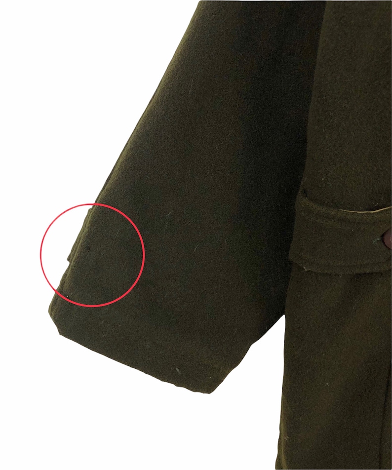 Pu&ograve; includere: Primo piano di una manica di cappotto verde oliva scuro. La manica &egrave; realizzata in un materiale spesso, forse lana. Il cappotto ha un design classico con una vestibilit&agrave; sartoriale. L'immagine evidenzia la trama e il colore del tessuto.