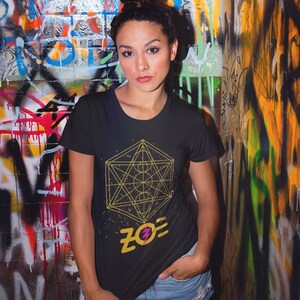 May include: A black t-shirt with a gold geometric design and the word "ZOE" in yellow with a pink lightning bolt.