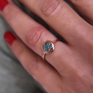 May include: A rose gold ring with a heart-shaped centre stone set with blue gemstones.