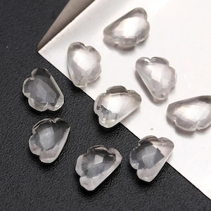 May include: Ten clear, faceted, cloud-shaped crystal stones on a silver tray. The stones are approximately 2.5 cm in size.