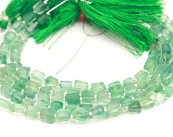 May include: A strand of faceted, translucent green fluorite beads arranged in a circular shape. The beads exhibit varying shades of light to dark green. A cluster of bright green thread tassels is attached to the top of the bead strand.