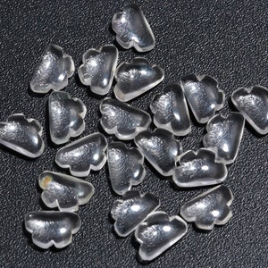 Könnte beinhalten: Eine Sammlung von durchsichtigen, wolkenförmigen Glasperlen. Die Perlen sind klein und haben eine glatte, polierte Oberfläche.