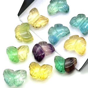 Peut inclure: Assortiment de perles de pierres précieuses en forme de papillon de différentes couleurs, notamment le vert, le bleu, le jaune, le violet et le marron.