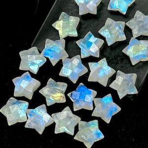 May include: A selection of star-shaped gemstones with a faceted design. The stones display a translucent white base with shimmering blue, yellow, and green hues. The stars are presented on a dark surface, highlighting their celestial quality.