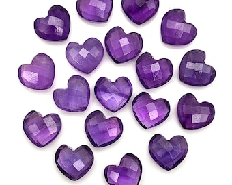 May include: A collection of faceted, heart-shaped amethyst gemstones. The gemstones are a deep purple color and are arranged on a white background. The hearts have a geometric cut, reflecting light.