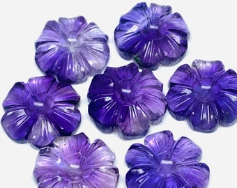 Könnte beinhalten: Sieben amethystfarbene, blumenförmige Cabochons. Die Cabochons sind tiefviolett mit einem helleren Lilaton in der Mitte. Die Cabochons sind alle ungefähr gleich groß und gleich geformt.