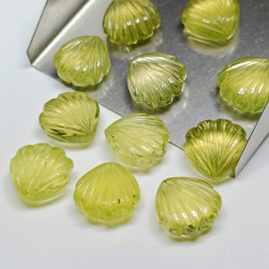 May include: A collection of ten green gemstone shell-shaped cabochons. The cabochons are carved with a detailed shell pattern and have a smooth, polished finish.