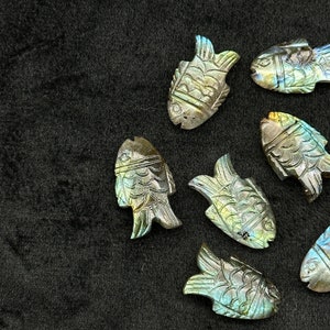 Puede incluir: Siete tallas de peces de labradorita iridiscente, cada una con un patr&oacute;n y una variaci&oacute;n de color &uacute;nicos. Las tallas son detalladas e intrincadas, mostrando la belleza natural de la piedra de labradorite.