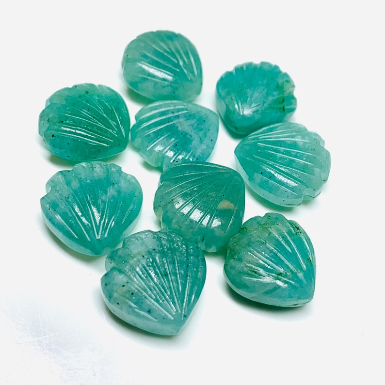 May include: Ten teal green heart-shaped gemstone beads with a carved seashell design.