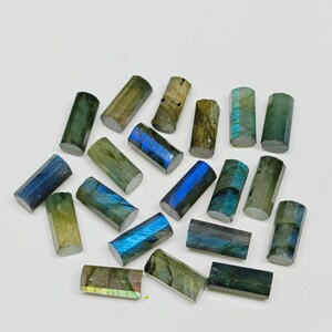 May include: A collection of 18 labradorite gemstone beads, each with a unique iridescent blue and green color. The beads are shaped like cylinders and have a smooth, polished finish.