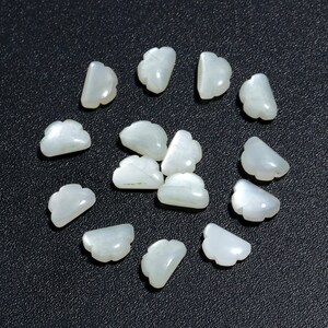 Op de afbeelding: Een verzameling witte parelmoer schelp kralen in een wolkvorm. De kralen zijn gerangschikt in een cirkel op een zwart oppervlak.
