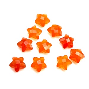 May include: Ten orange star-shaped carnelian gemstones. The stones are faceted and have a polished finish.