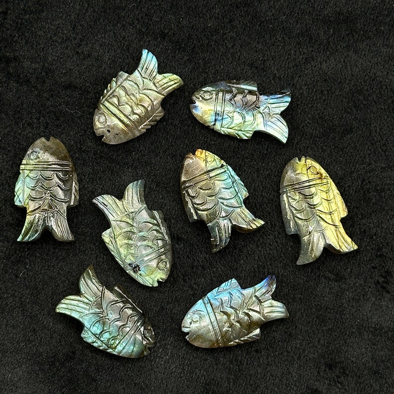 Puede incluir: Ocho tallas de peces de labradorita iridiscente, cada una con un patr&oacute;n y una variaci&oacute;n de color &uacute;nicos. Las tallas son detalladas e intrincadas, mostrando la belleza natural de la piedra de labradorita.