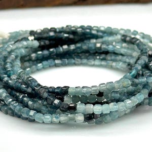 May include: A strand of blue apatite beads, faceted and square shaped, with a graduated colour from dark blue to light blue.