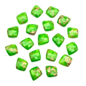 May include: A collection of 18 green and gold square-shaped cabochons. The cabochons are arranged in a circle on a white background.