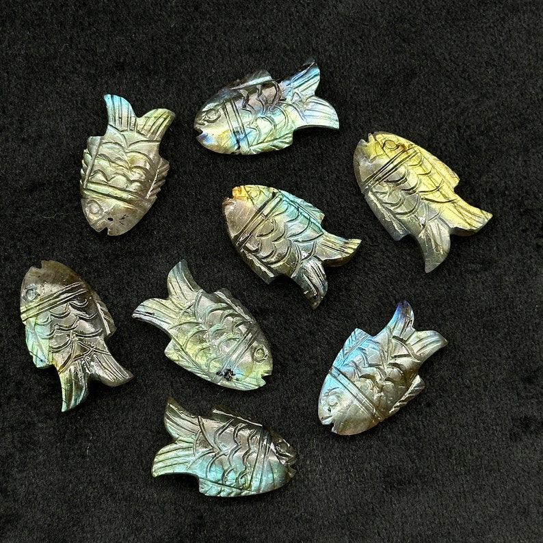 Puede incluir: Ocho tallas de peces de labradorita iridiscente, cada una con un patr&oacute;n y una variaci&oacute;n de color &uacute;nicos. Las tallas son pulidas y lisas, con detalles intrincados.