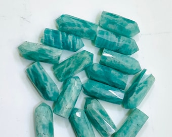 May include: A collection of 14 teal green amazonite crystal points. The points are smooth and polished, with a natural, striated texture.
