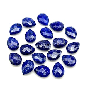May include: A collection of 18 pear-shaped lapis lazuli gemstones. The stones are a deep blue color with flecks of gold pyrite.