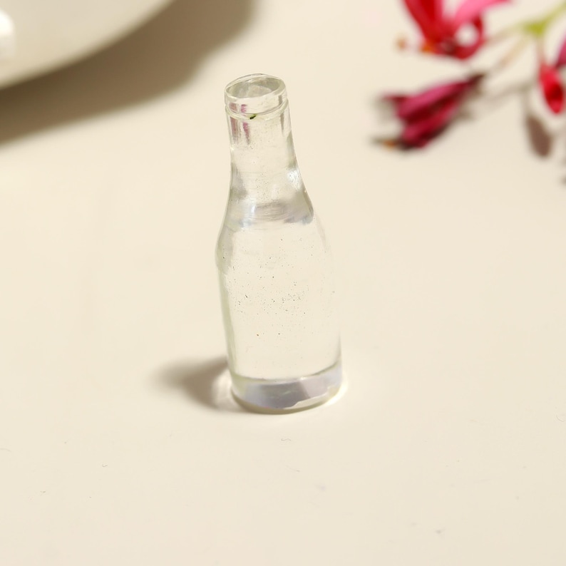 Puede incluir: Una botella de vidrio transparente con una superficie texturizada. La botella est&aacute; vac&iacute;a y tiene un fondo redondeado.