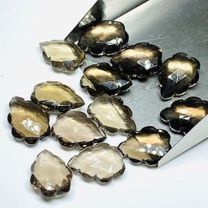May include: A collection of 14 faceted, smoky quartz leaf-shaped gemstone beads. The beads are a light brown color with a translucent finish.