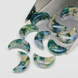 May include: A collection of green, white and blue agate crescent moon shaped stones. The stones are arranged on a silver tray.