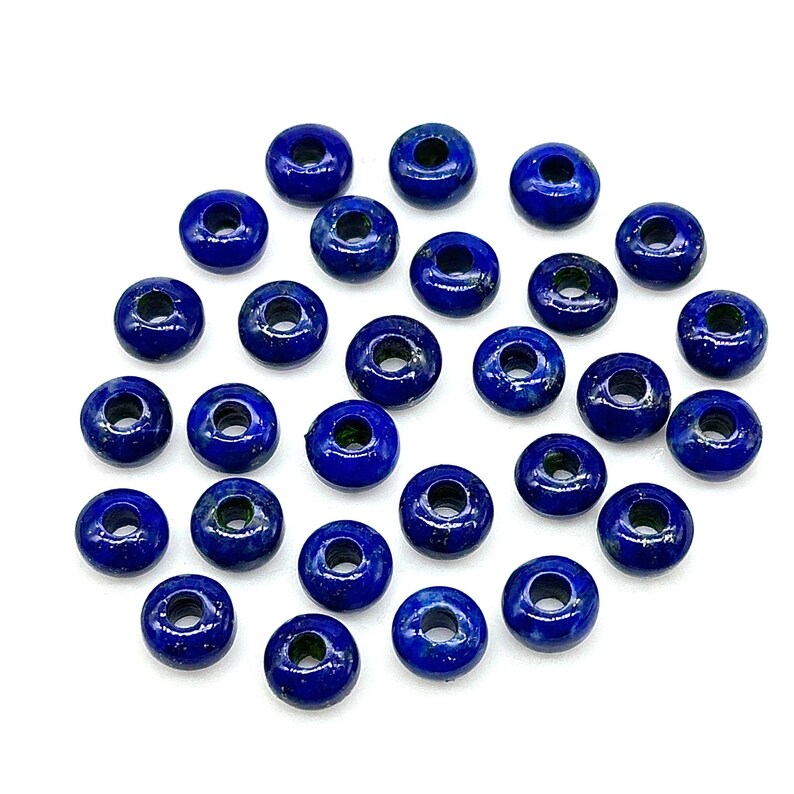 May include: A collection of 30 round, dark blue lapis lazuli beads with a hole in the center. The beads are approximately 1/2 inch in diameter.