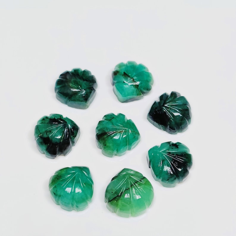 Puede incluir: Ocho cabujones de piedra preciosa esmeralda verde tallados en forma de hojas. Las piedras preciosas son facetadas y tienen un color verde oscuro.