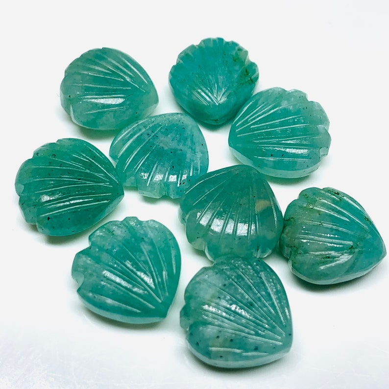 May include: Nine teal green carved gemstone heart-shaped shells. The shells have a detailed carved design.