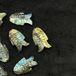 Puede incluir: Una colecci&oacute;n de esculturas de peces de labradorita iridiscente. Los peces est&aacute;n tallados en piedra de labradorita natural y tienen una variedad de colores, incluyendo azul, verde y dorado.