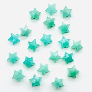 May include: A collection of 20 teal green star-shaped gemstone beads. The beads are faceted and have a smooth, polished finish.
