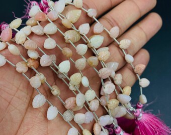 May include: A strand of pink opal leaf-shaped beads strung on silver wire. The beads are approximately 10mm in size and have a natural, irregular shape. The strand is finished with pink tassels.