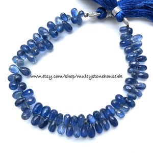 May include: A strand of blue gemstone beads, with a blue tassel at the end. The beads are faceted and have a teardrop shape. The beads are strung on a clear thread. www.etsy.com/shop/multystonehousehk