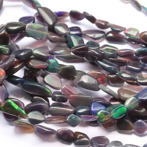 May include: A strand of dark iridescent opal beads, each bead is a unique, freeform shape with a smooth, polished finish.