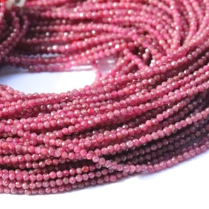May include: A strand of ruby red gemstone beads. The beads are faceted and have a slightly irregular shape. The strand is approximately 16 inches long.
