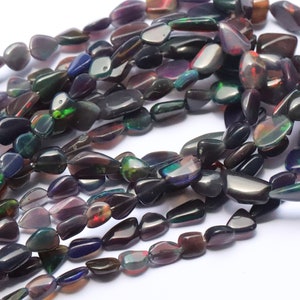 May include: A strand of dark, iridescent, teardrop-shaped opal beads. The beads have a black base with flashes of green, red, and purple.