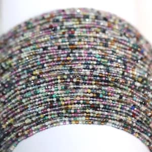 May include: Close-up of a multi-colored beaded necklace. The beads are small and round, in shades of pink, green, blue, and brown. The necklace is likely a fashion accessory.