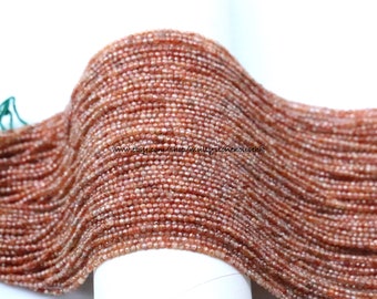 May include: A strand of orange sunstone beads, approximately 2mm in size. The beads are faceted and have a shimmery, iridescent finish. The strand is wound into a coil shape.