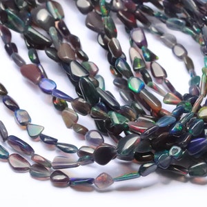 May include: A strand of iridescent black opal gemstone beads. The beads are teardrop shaped and have a smooth, polished finish.