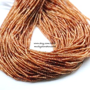 May include: A strand of small, faceted, orange-brown gemstone beads. The beads are strung on a clear thread and are approximately 2 mm in diameter. The beads are arranged in a loose, flowing pattern. www.etsy.com/shop/multistonehousehk