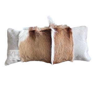 May include: A long rectangular pillow with a brown and white fur cover. The pillow has a light gray suede backing.