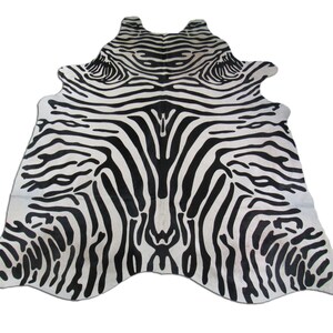May include: Black and white zebra print cowhide rug. The rug has a natural, irregular shape and is made of real cowhide.