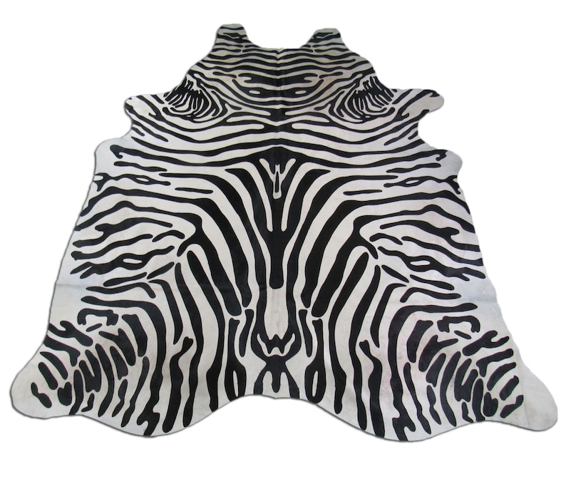May include: Black and white zebra print cowhide rug. The rug has a natural, irregular shape and is made of real cowhide.
