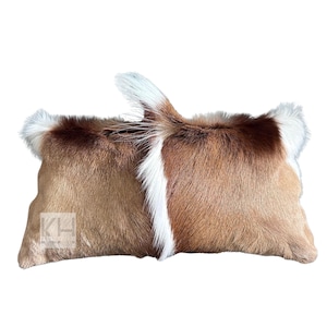May include: Two brown and white fur throw pillows with a long, rectangular shape. The pillows are made of a soft, plush material and have a natural, rustic look.