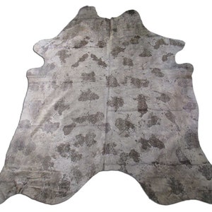 Op de afbeelding: Een koeienhuidkleed in een lichtbruine en witte kleurstelling. Het kleed heeft een natuurlijke, verweerde uitstraling met een subtiel patroon.