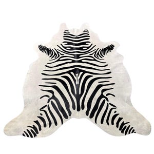 May include: A hide rug featuring a high-contrast black and white zebra stripe pattern. The animal-shaped rug has an irregular, organic outline with a dense arrangement of horizontal and diagonal black stripes against a white background.