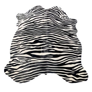 May include: An irregular, hide-shaped rug featuring a high-contrast black and white zebra stripe pattern. The design consists of flowing, organic lines that mimic natural animal markings across the entire surface of the flat floor covering.