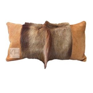 May include: A rectangular brown suede pillow with a brown and tan fur insert. The fur has a long, flowing texture.