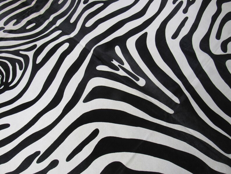 May include: Black and white zebra print fabric with a smooth, shiny texture.