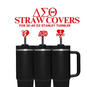 May include: Three black 30-40 oz Stanley tumblers with red straw covers. The straw covers feature different designs: a heart with Greek letters, Greek letters, and an elephant with Greek letters.