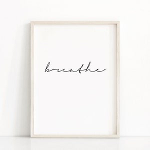 K&ouml;nnte beinhalten: Ein wei&szlig;er gerahmter Druck mit dem Wort "breathe" in schwarzer Kursivschrift.